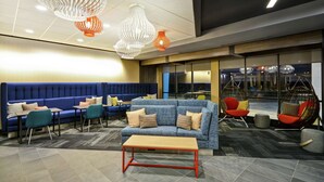 A modern lounge area with a blue sofa set, teal chairs, and a wooden coffee table. - Tru by Hilton Huber Heights (Dayton)