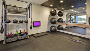 A gym with exercise equipment, a mirror, and a digital screen. - Tru by Hilton Huber Heights (Dayton)
