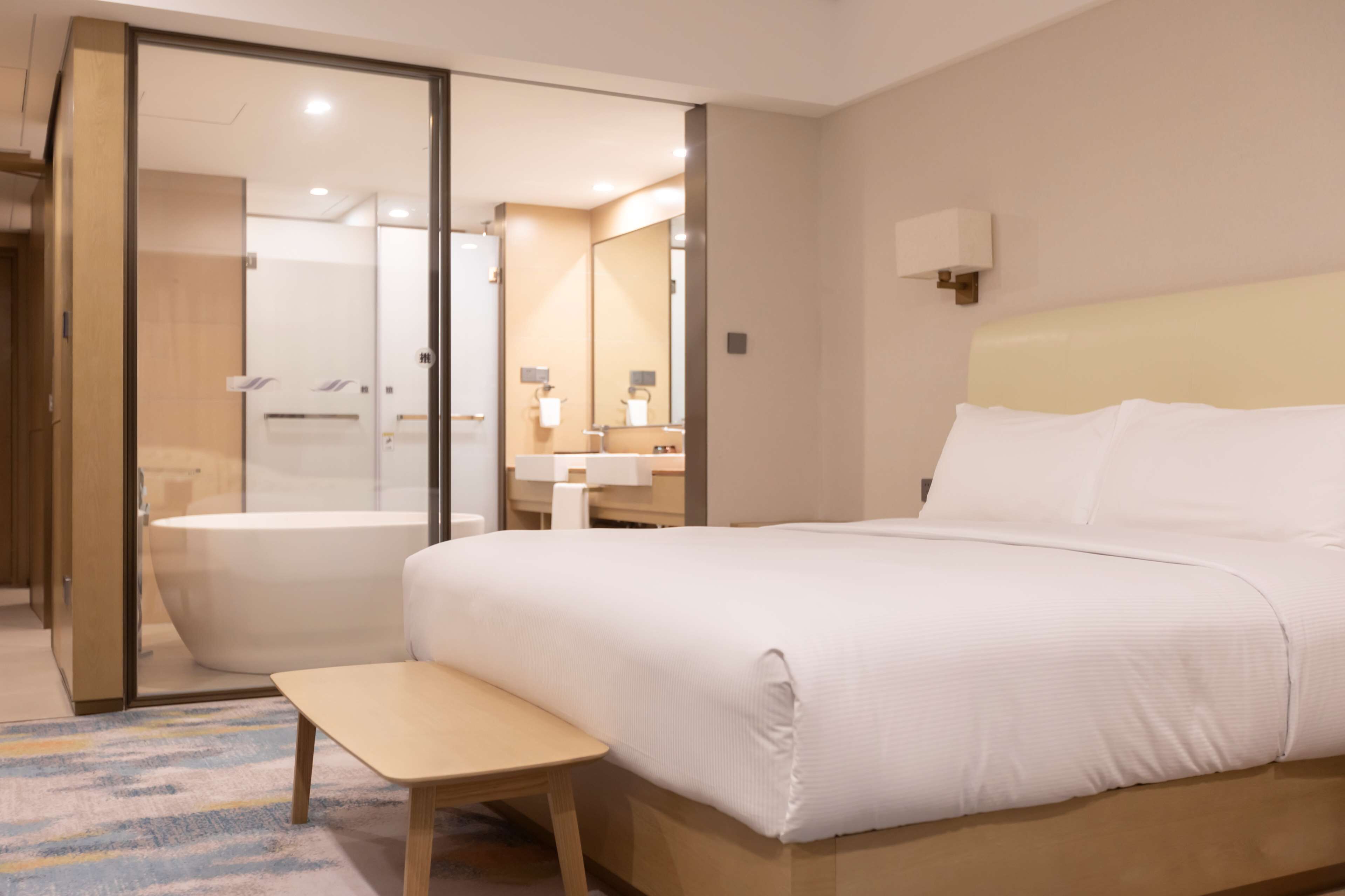 A hotel room with a large bed, a small table, a bathroom with a bathtub, and a mirror.