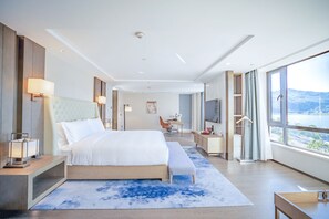 A modern hotel room with a large bed, a desk, a TV, and a view of the outdoors. - Hilton Lijiang (Lijiang)