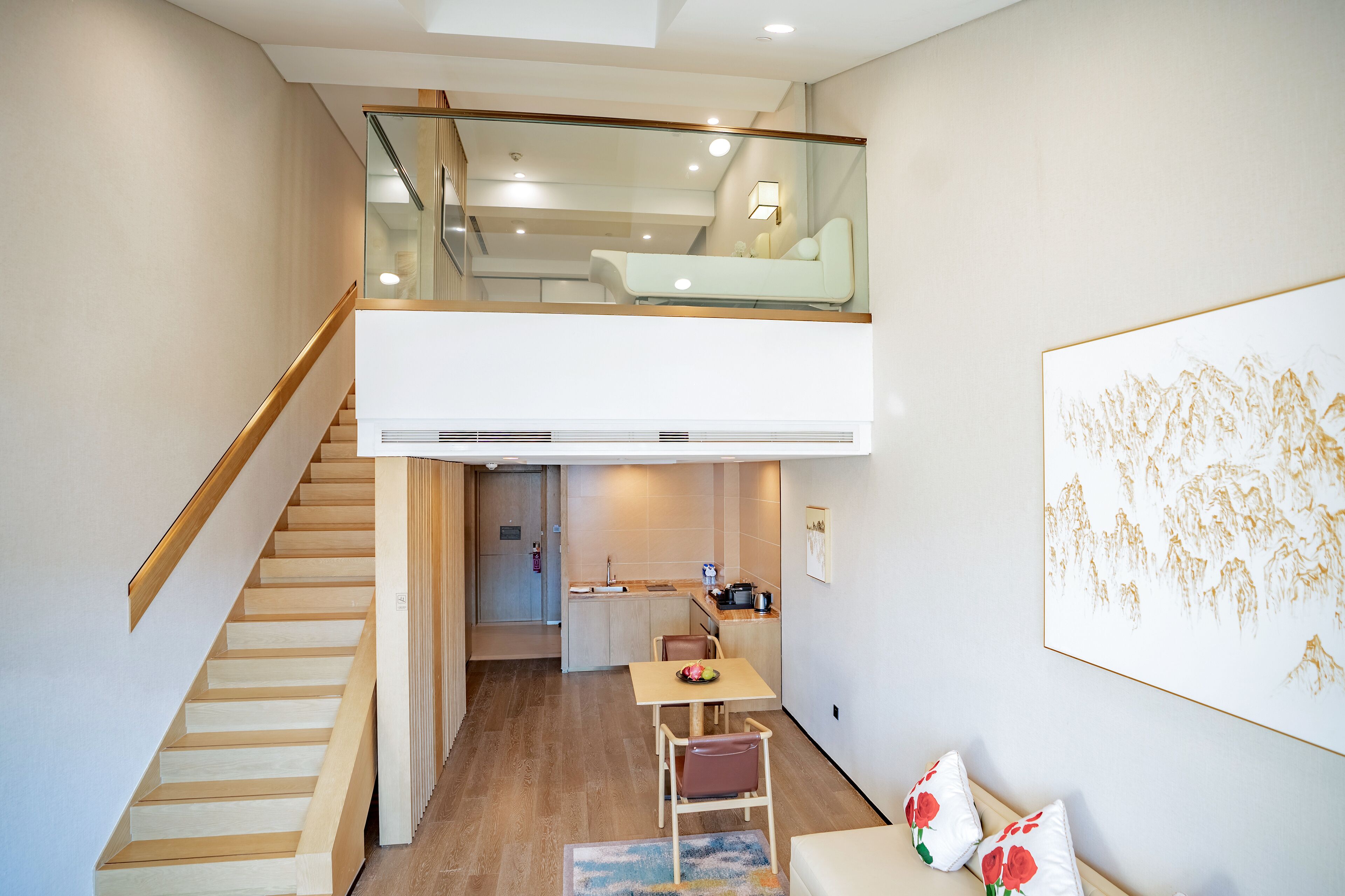 A modern interior with a staircase leading to a loft bedroom, a dining area, and a kitchen.