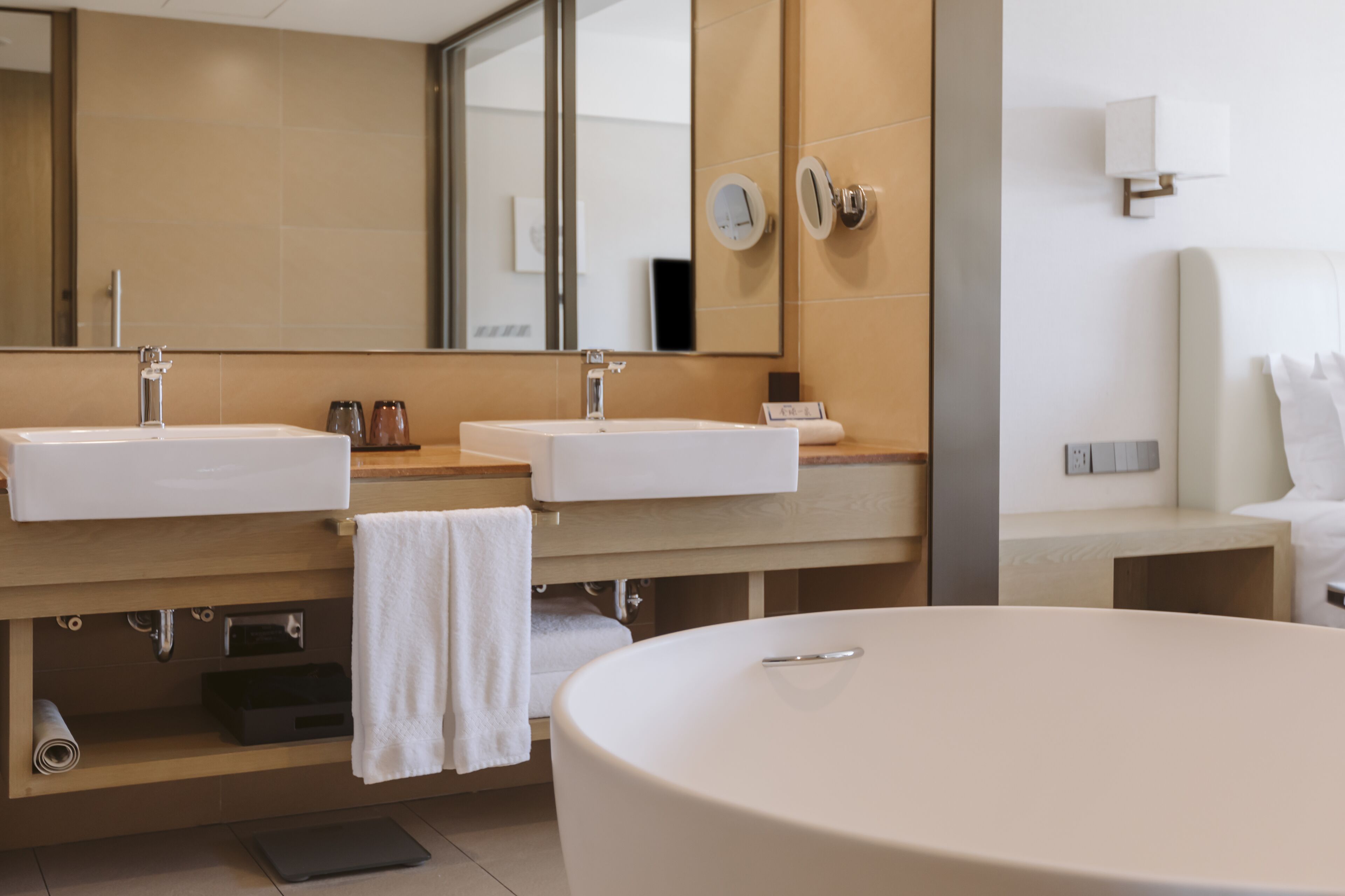 A modern bathroom with two sinks, a large bathtub, and a mirror.