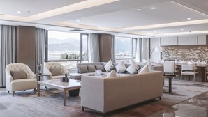 A modern living room with a sofa, armchairs, and a coffee table. There is a view of mountains through large windows. - Hilton Lijiang (Lijiang)