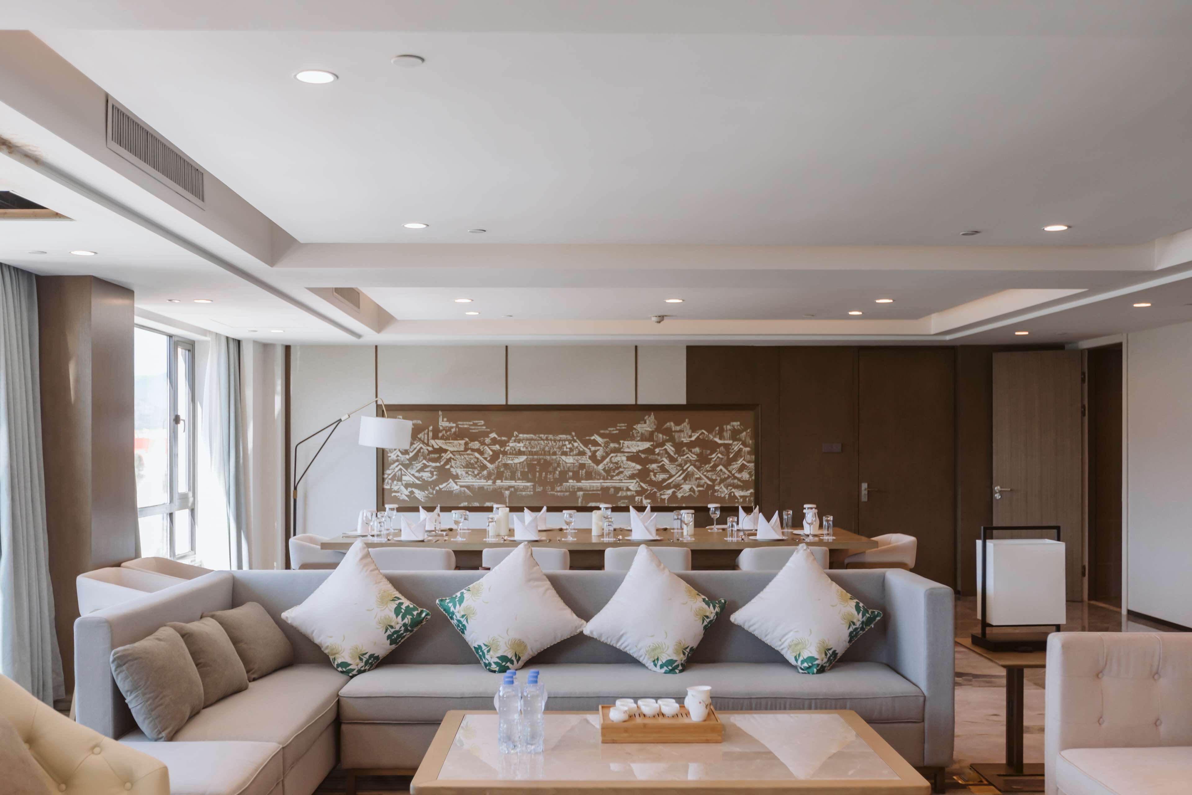 A modern hotel lobby with a sofa set, a coffee table with amenities, and a decorative wall.