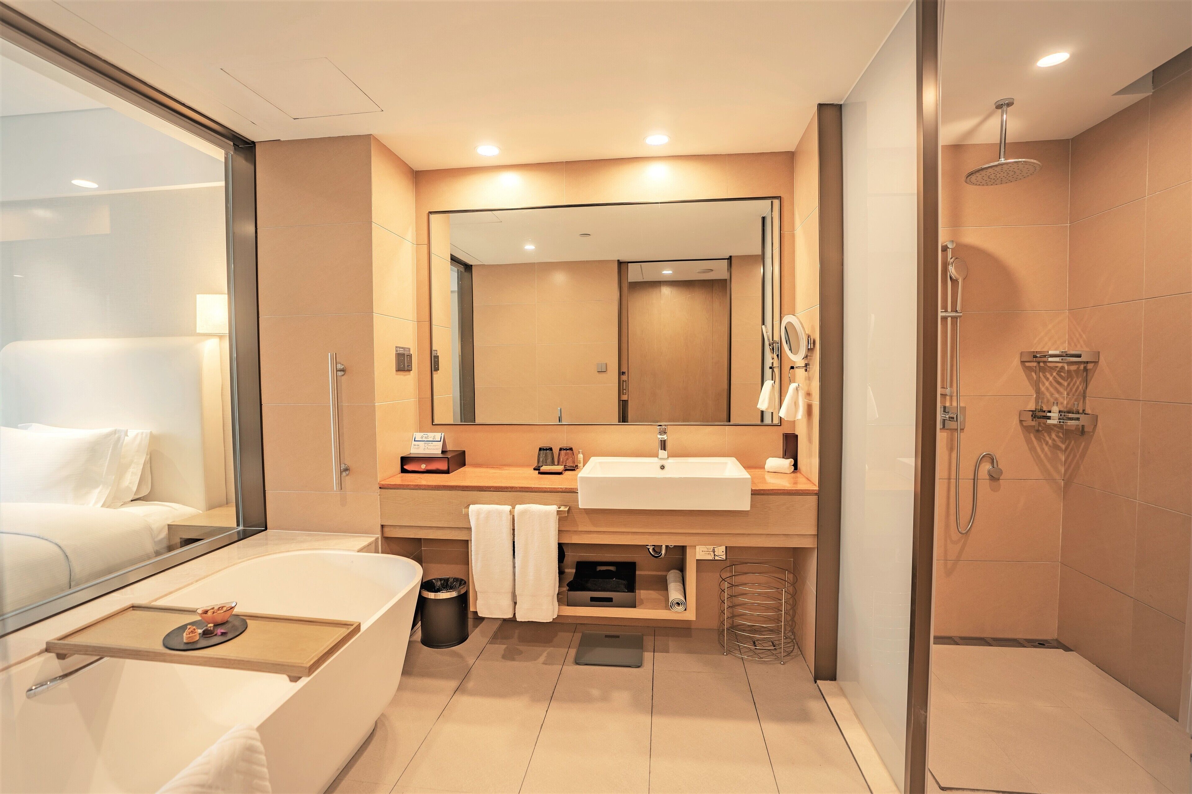 Un baño moderno con un espejo grande, una bañera, una ducha y un lavabo con toallero.