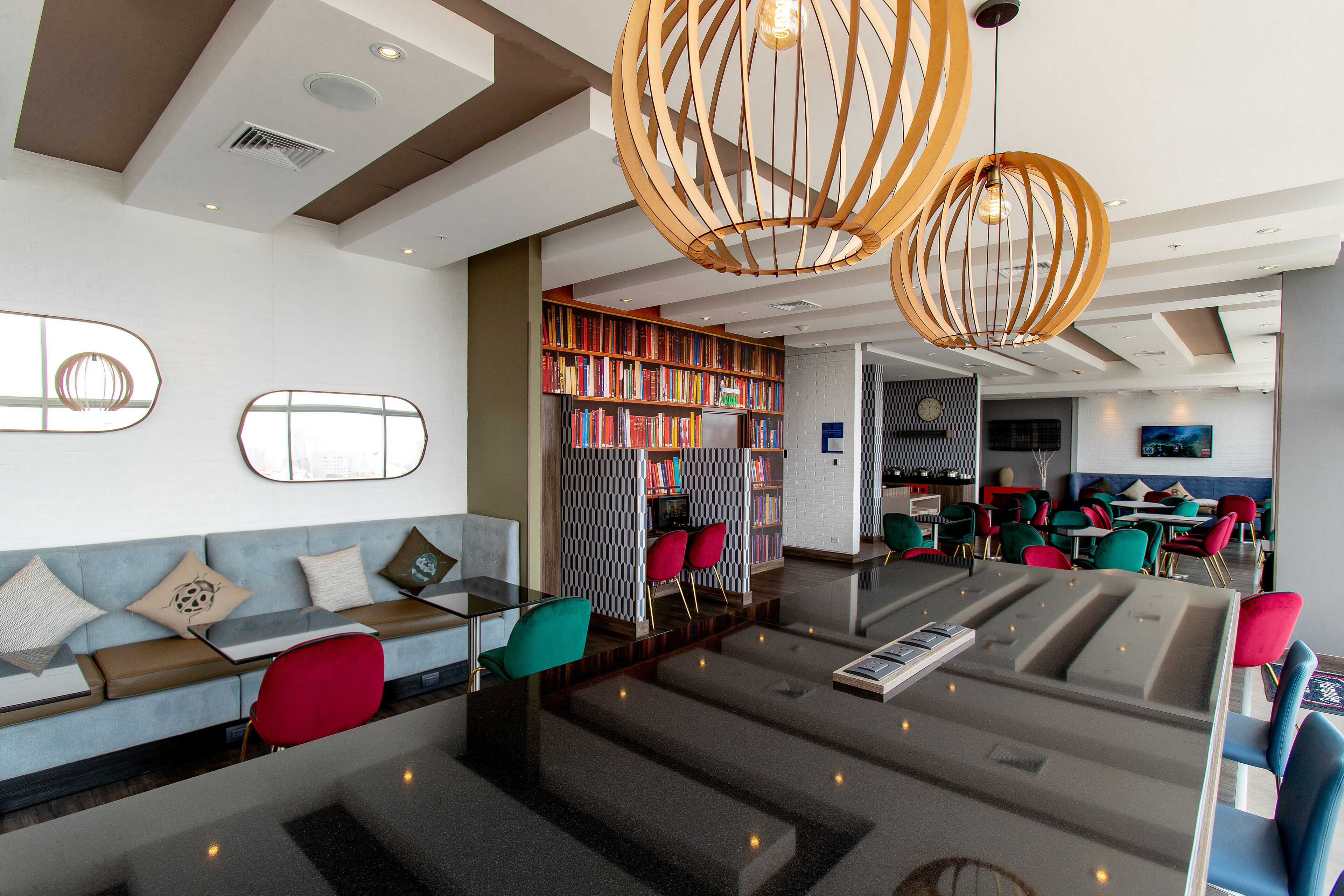 Eine moderne Hotelhalle mit Sitzgelegenheiten, Bücherregalen und einem Essbereich.