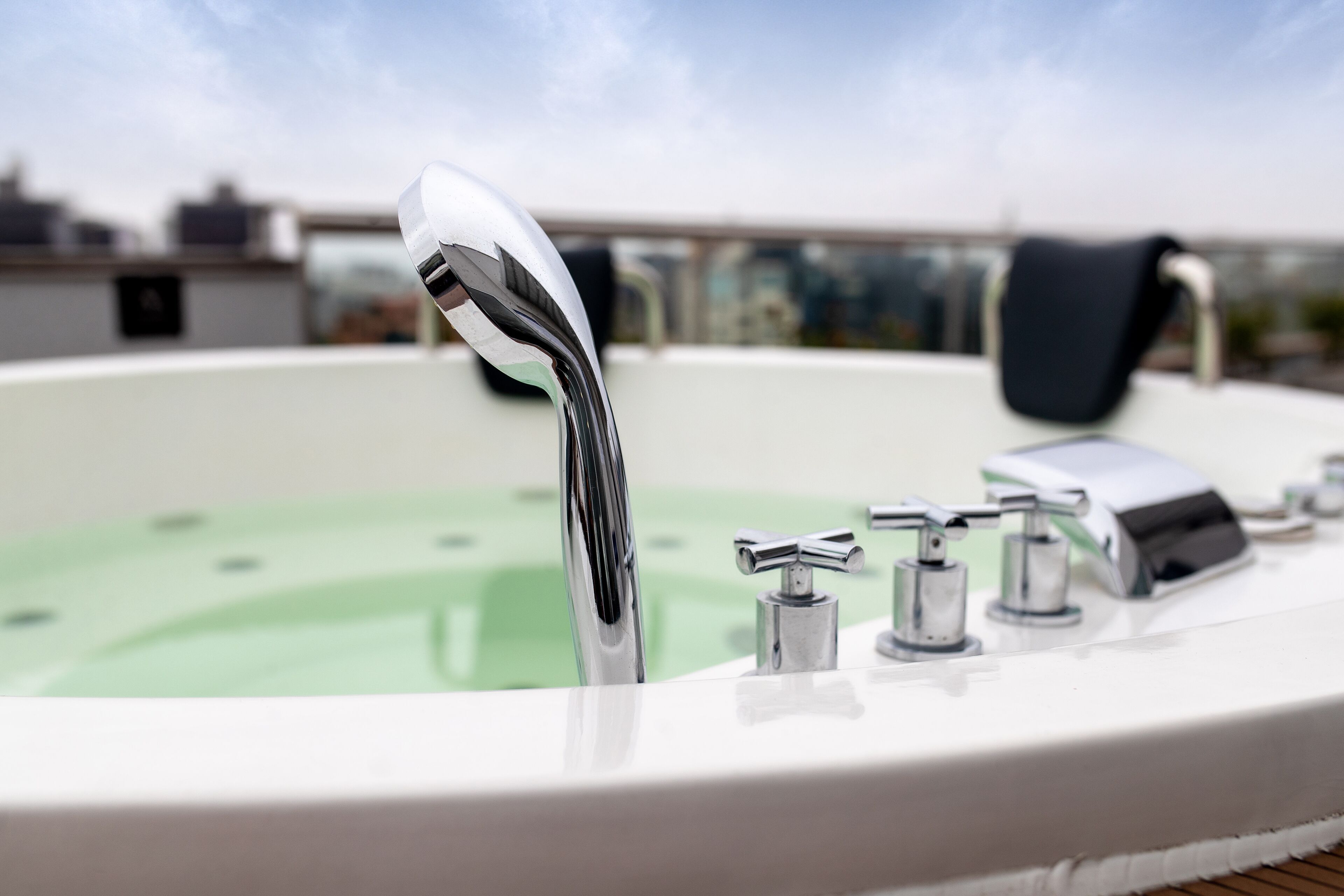 A hot tub with multiple faucets and a clear view of the sky in the background.