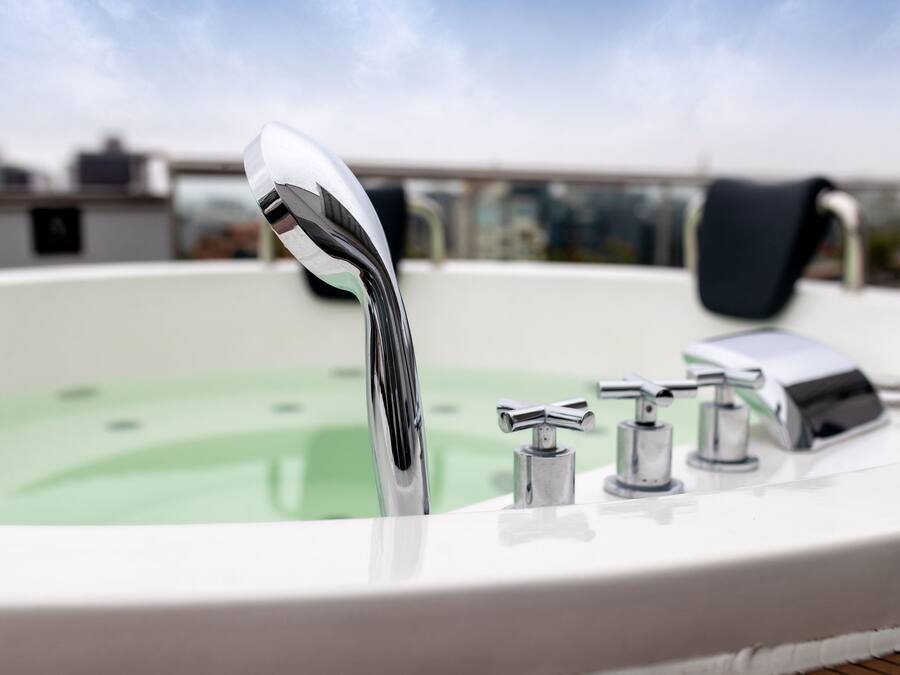 A hot tub with multiple faucets and a clear view of the sky in the background.