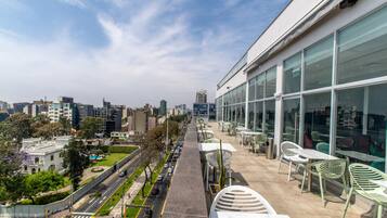 A city view from a balcony with a street, trees, and modern buildings.
