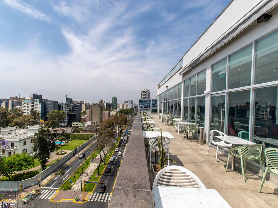 A city view from a balcony with a street, trees, and modern buildings.