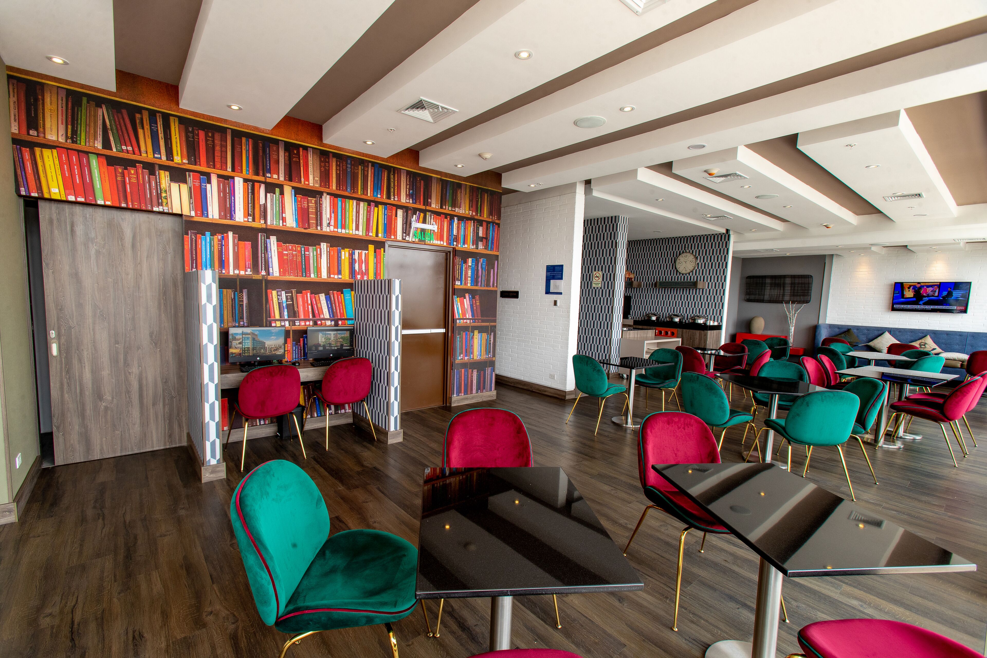 Uma biblioteca moderna com estantes, assentos confortáveis e uma televisão.