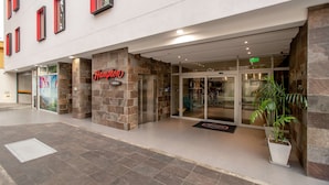 A hotel entrance with a stone facade, glass doors, and a sign reading "Hampton." - Hampton by Hilton Lima San Isidro (Lima)
