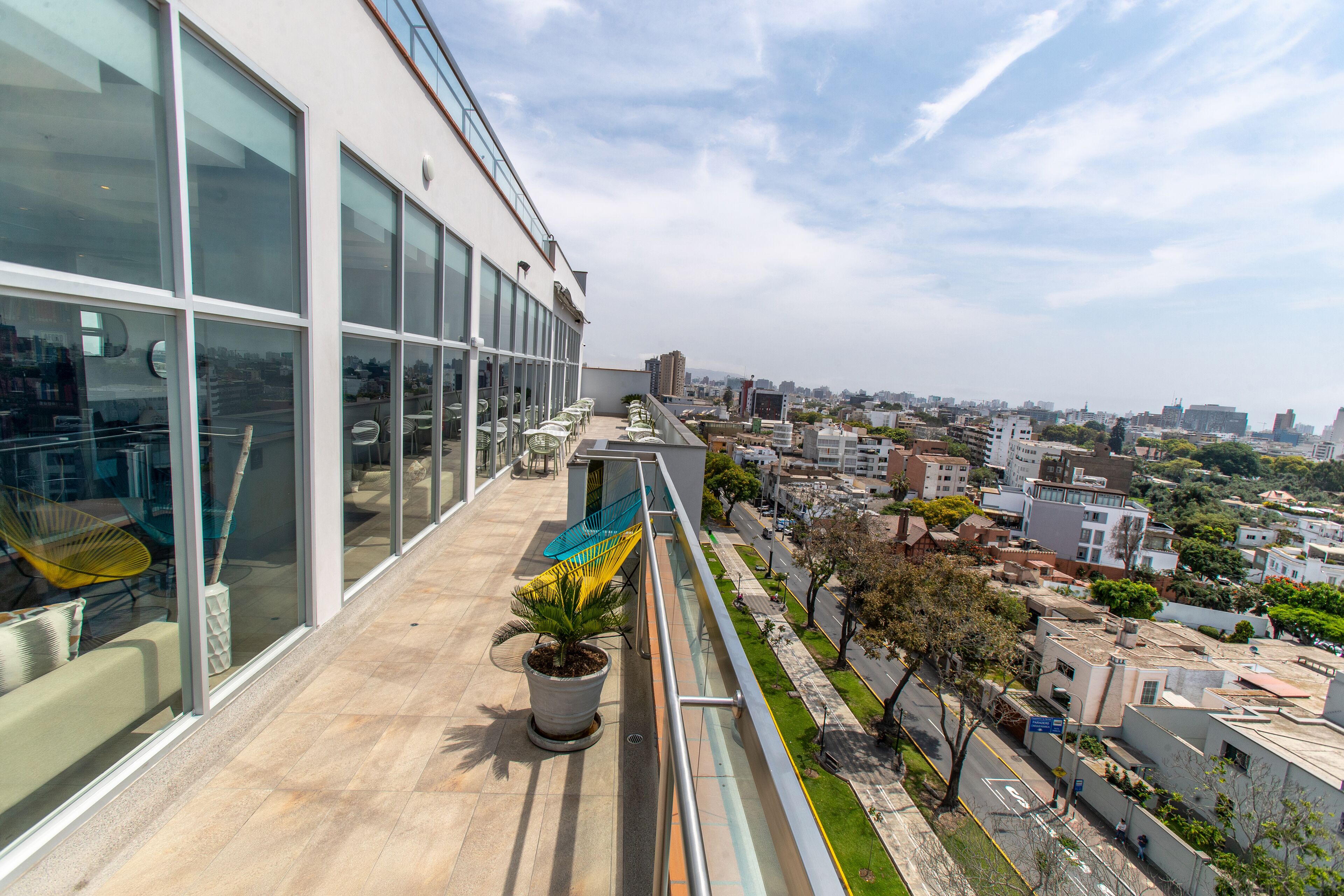 Un edificio moderno con ventanas amplias y un balcón que da a una vista urbana.