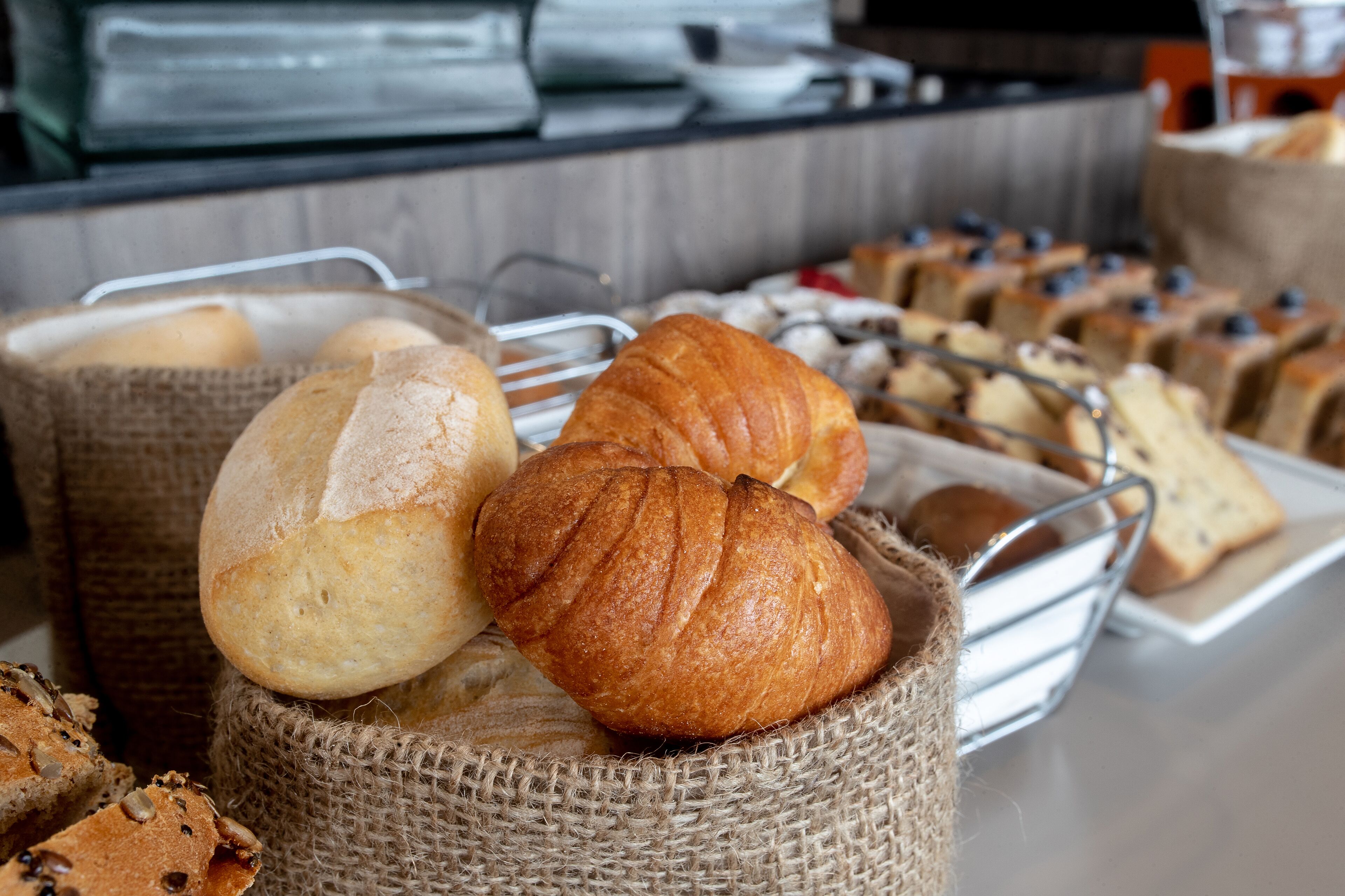 Diverse gebakken producten, waaronder brood en gebak, gepresenteerd in manden en op een schaal.
