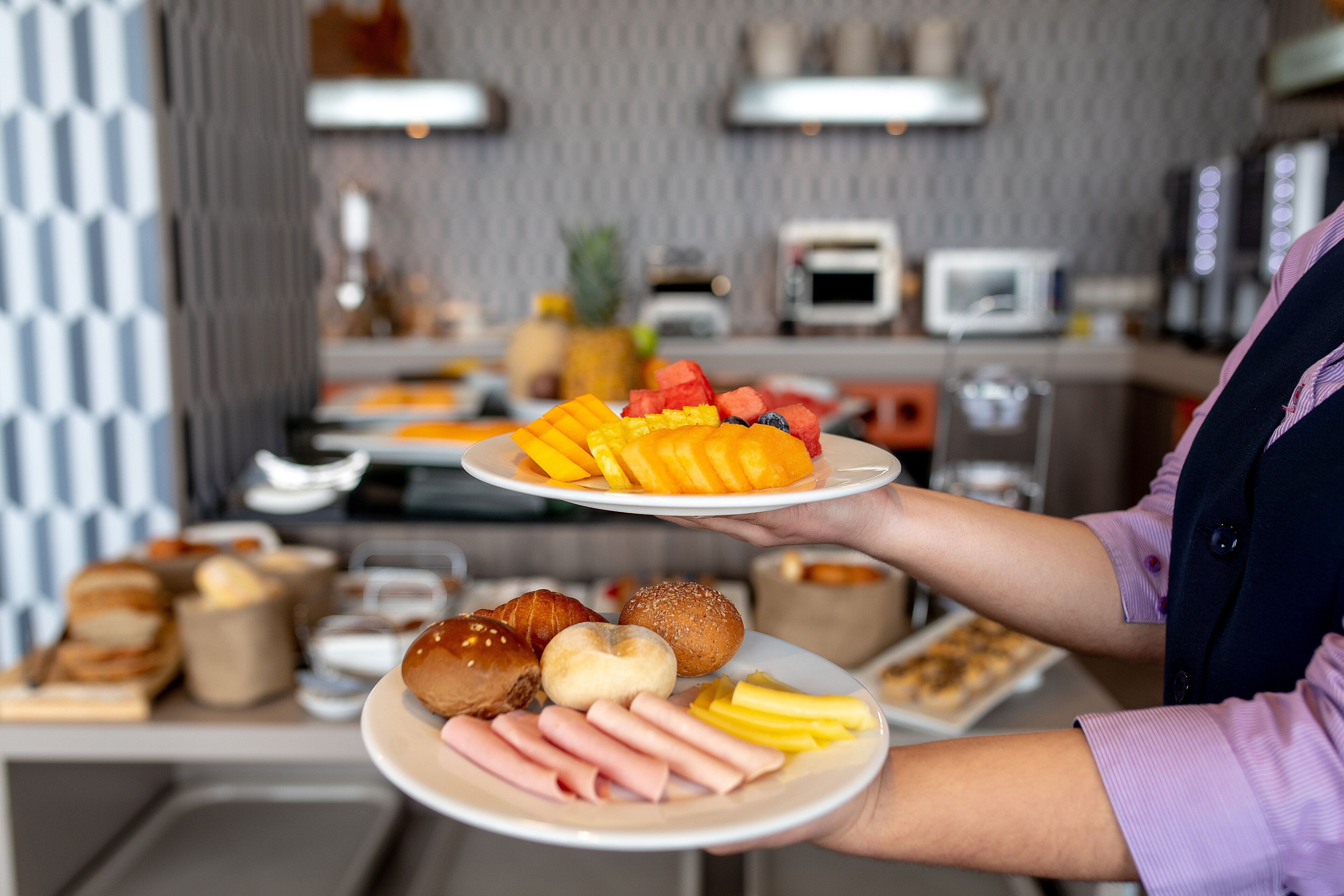 Montaje de bufé con diversos alimentos, entre ellos frutas, pasteles y carnes.