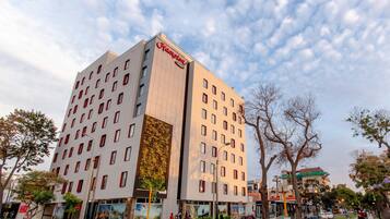 A modern hotel with a prominent 'Hampton' sign, multiple floors, and a large vertical garden feature.