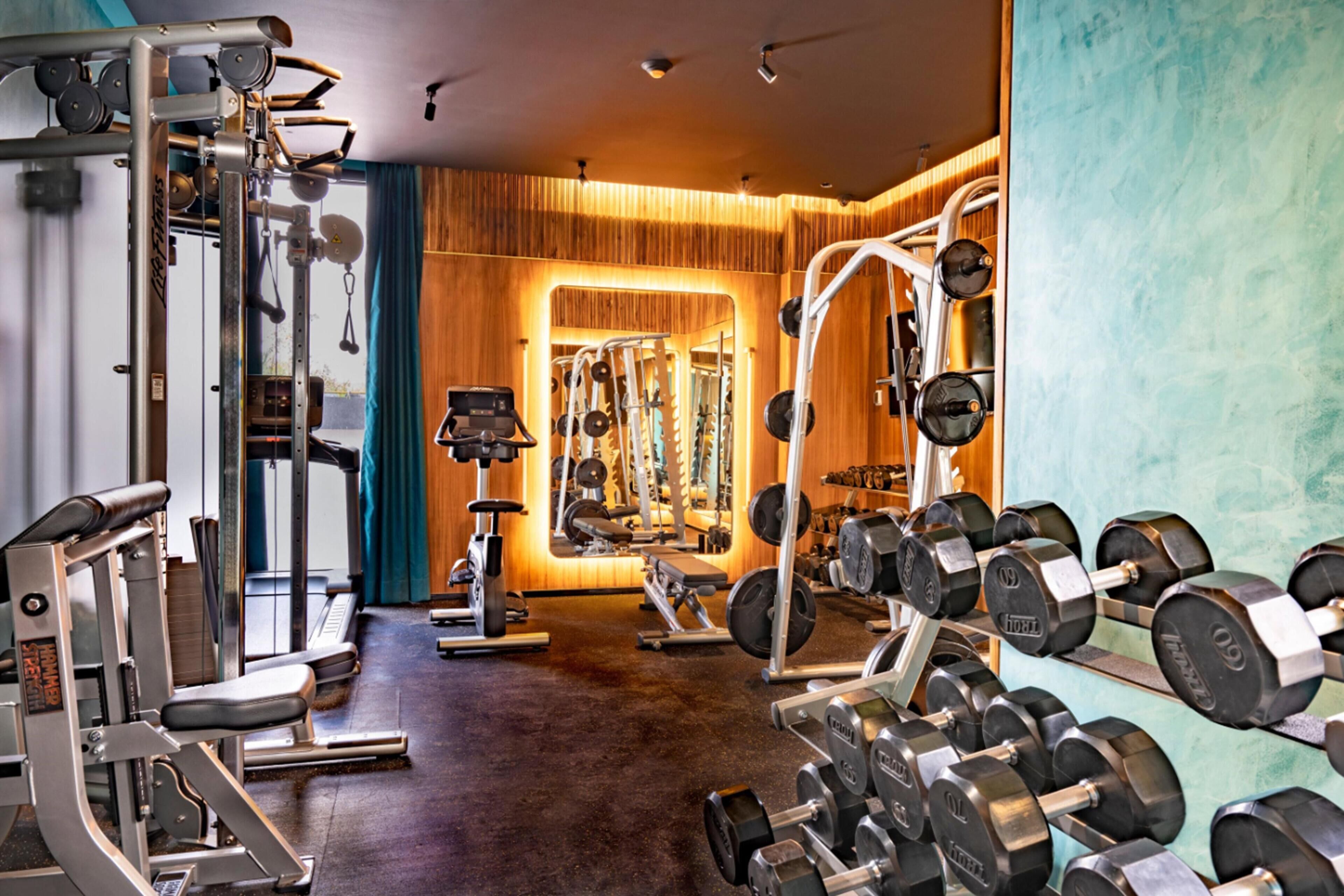 Een sportschool met diverse trainingsapparaten, waaronder gewichten en krachtapparaten.