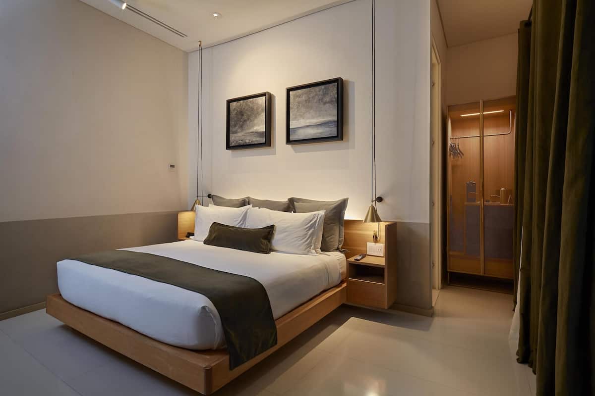 A modern bedroom with a large bed, bedside tables, and artwork on the wall.