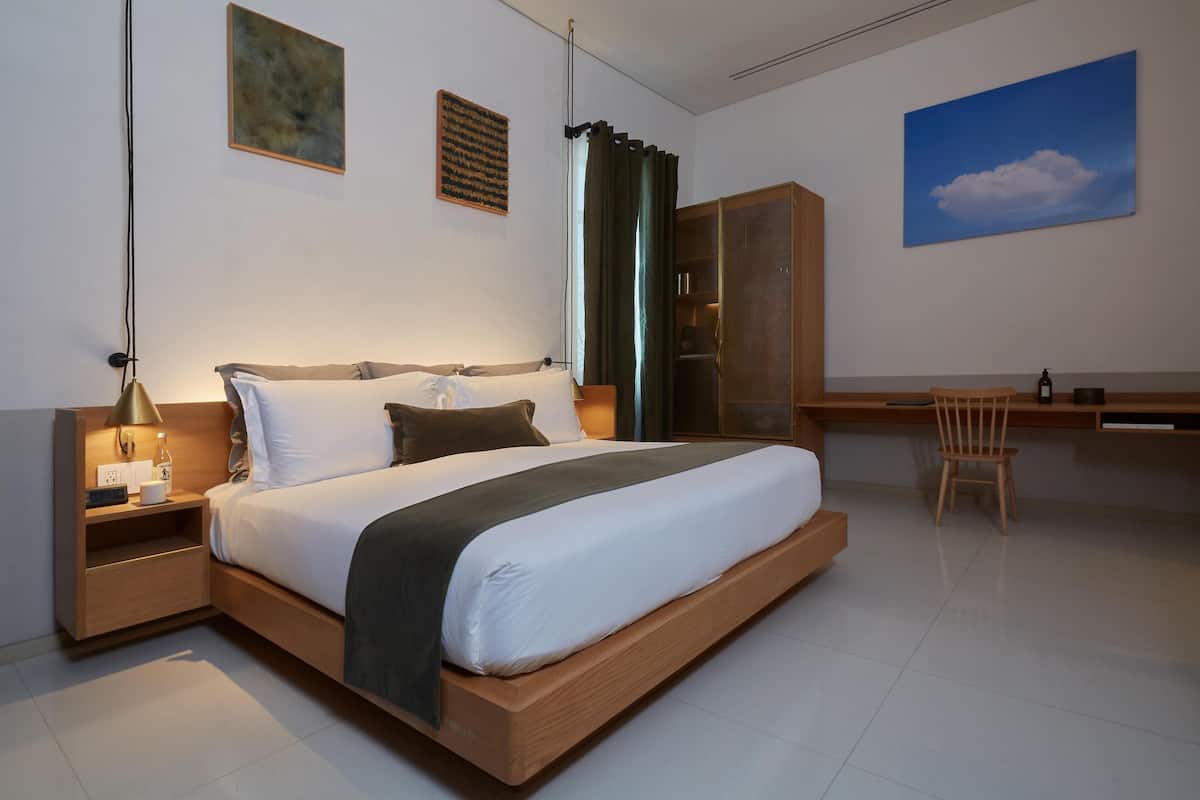 A modern bedroom with a large bed, bedside tables, a desk, and a chair.