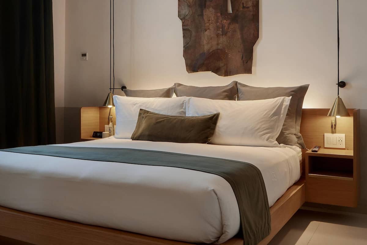 A modern bedroom with a large bed, wooden headboard, and a unique abstract wall art piece.