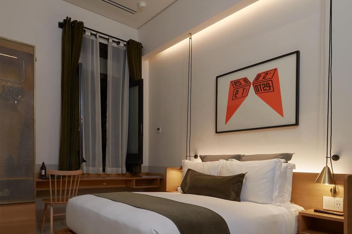 A modern bedroom with a wooden bed, a TV, and a framed artwork on the wall.
