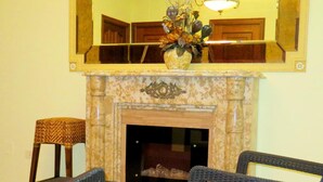 A living room with wicker furniture, a fireplace, and a large mirror above it. - Hotel Restaurante América (A Estrada)