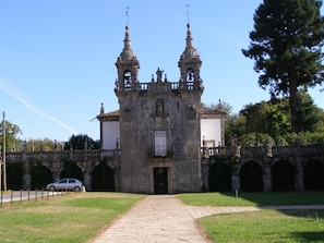 A historic building with a central entrance, two bell towers, and a surrounding stone wall. - Hotel Restaurante América (A Estrada)
