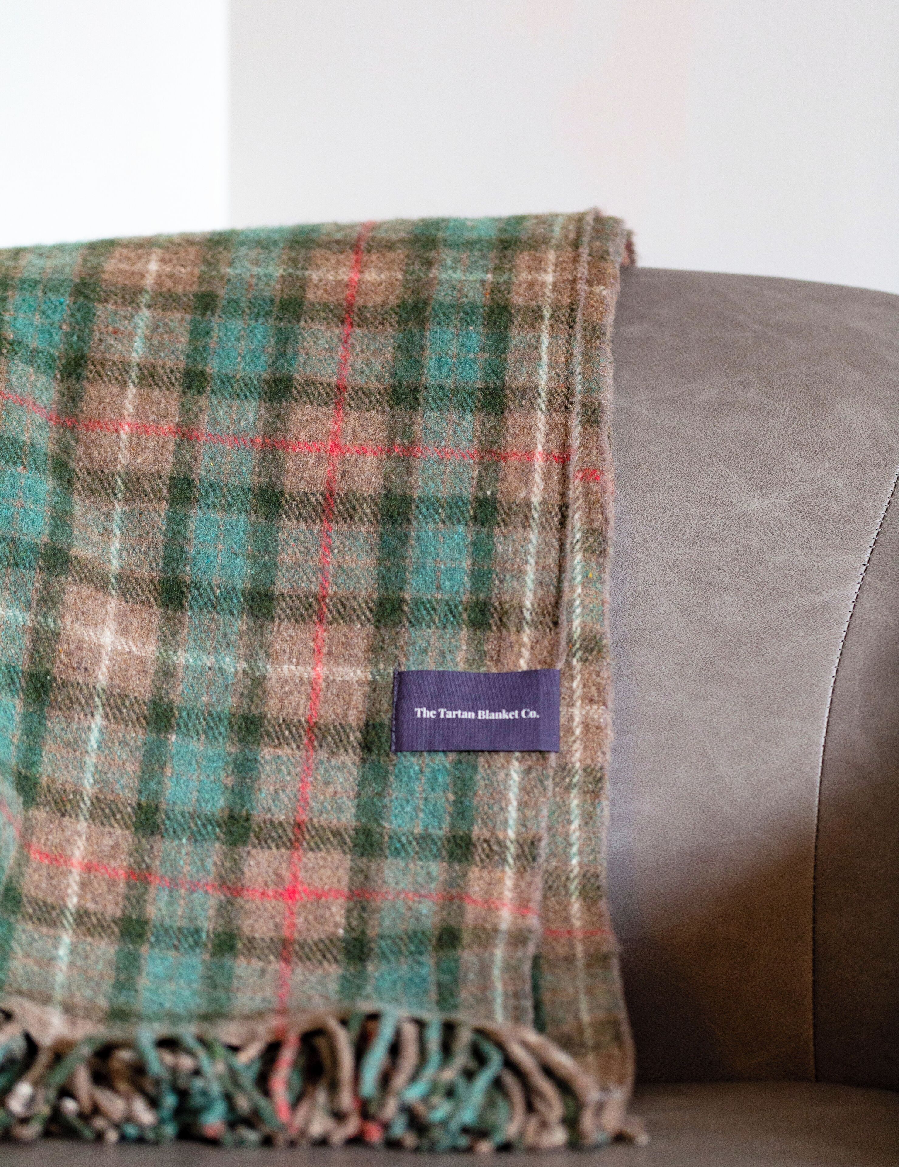 A plaid blanket with a label on a leather couch.