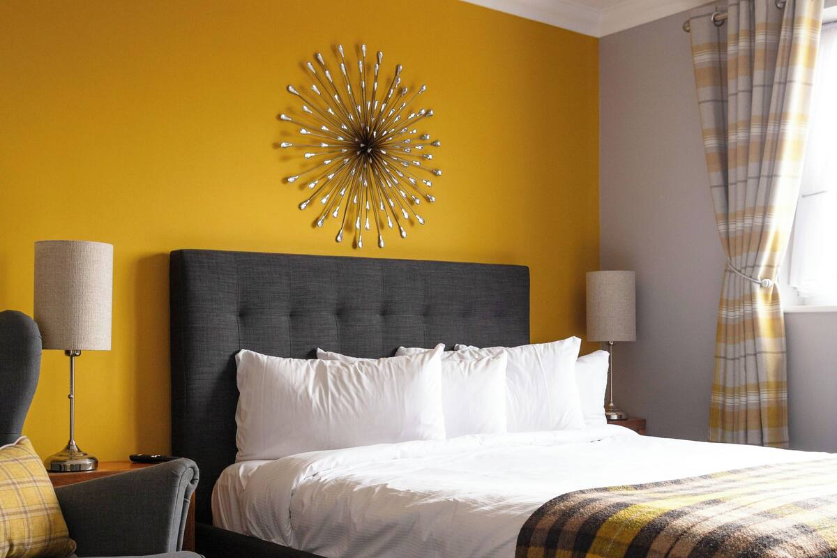 A bedroom with a bed, a chair, a lamp, and a wall decoration.