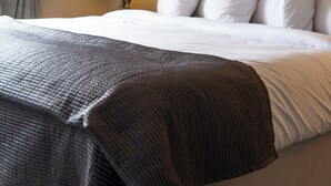 A hotel room with a large bed, a nightstand with a lamp, and two framed pictures on the wall. - Bojangles Guest House (Gretna)