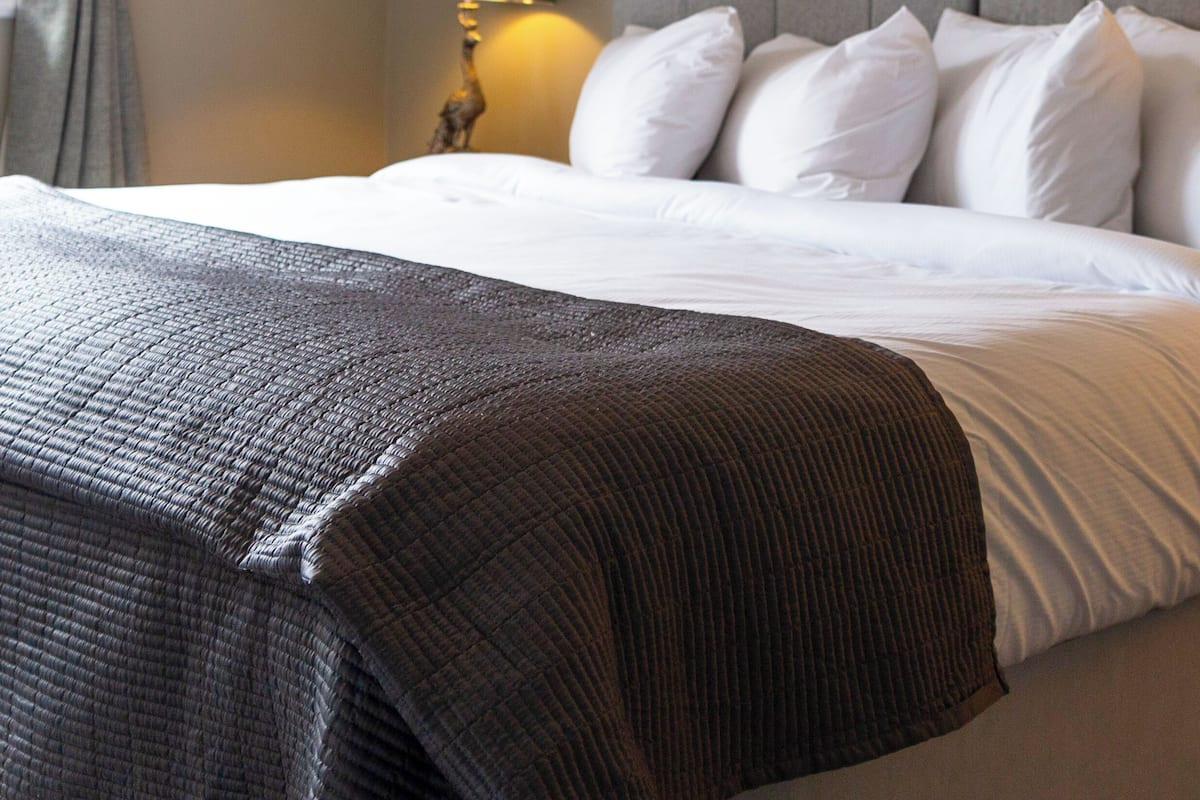 A hotel room with a large bed, a nightstand with a lamp, and two framed pictures on the wall.