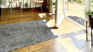 A bright room with two chairs, a small table, and a potted plant. There is a large window and a door leading to an outdoor area. - Bojangles Guest House (Gretna)