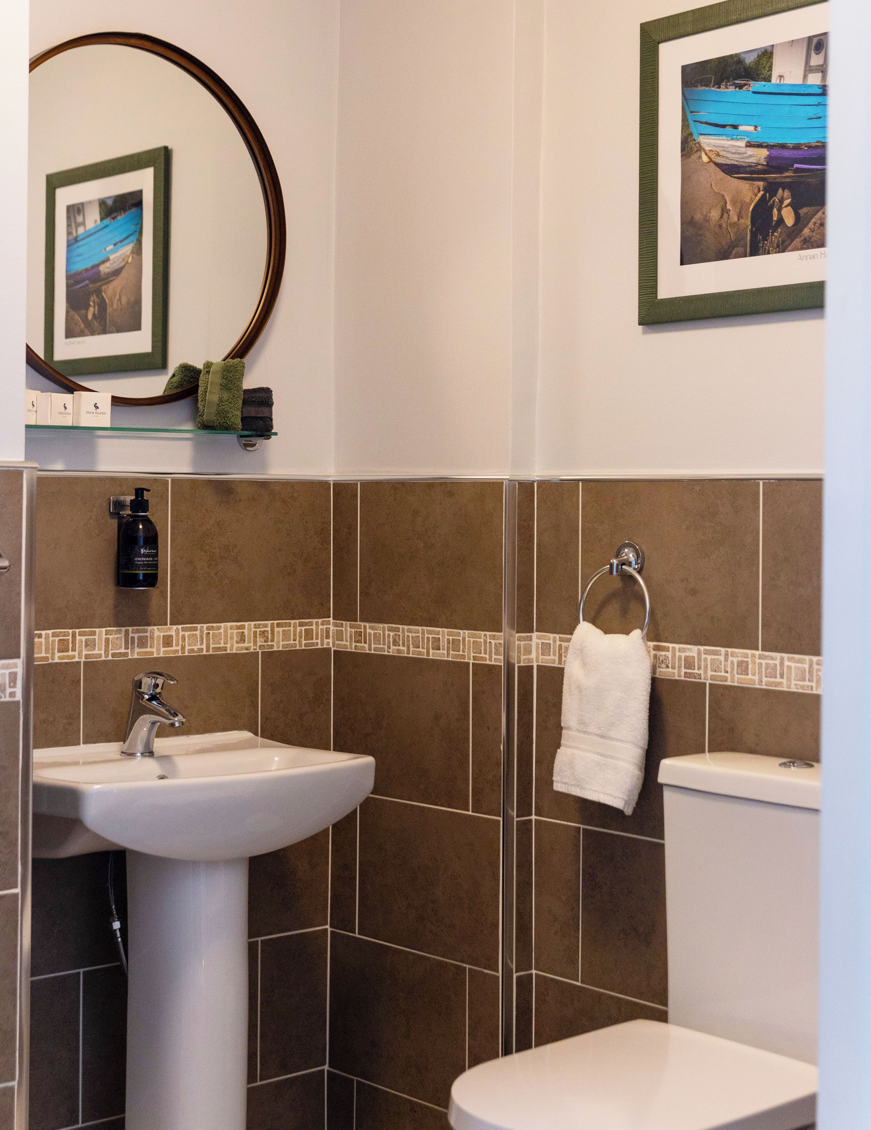 A bathroom with a sink, toilet, and a framed picture on the wall.
