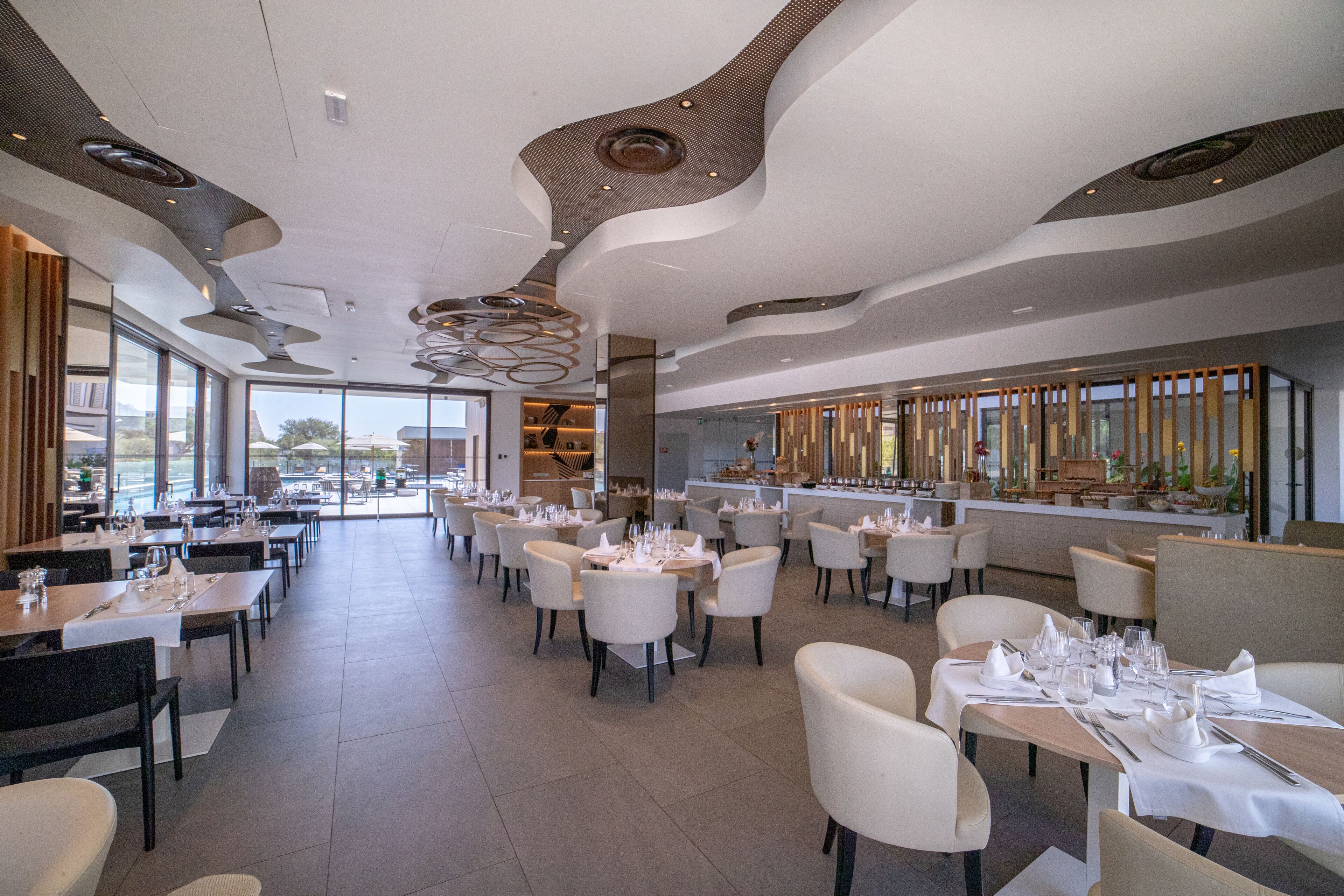 Un restaurante moderno con un amplio comedor, techos altos y grandes ventanales.