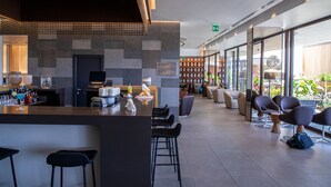 Een moderne barruimte met een toonbank, krukken en een zithoek met stoelen en tafels.