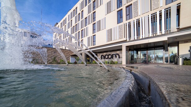 Een modern gebouw met een waterpartij ervoor.
