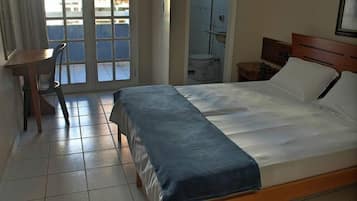 Habitación de hotel con cama, escritorio, silla y vistas al exterior a través de una ventana.