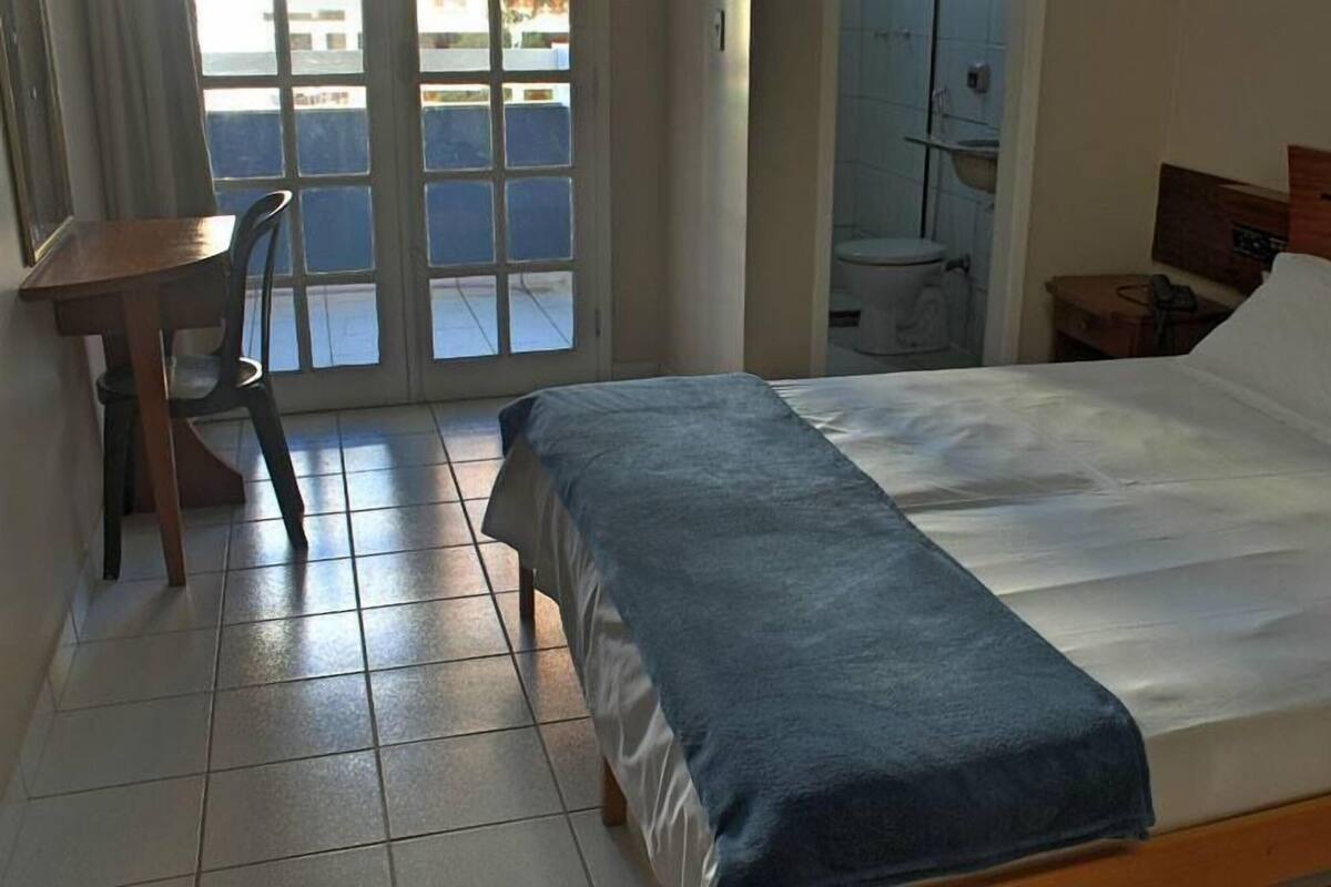 A hotel room with a bed, a desk, and a chair.