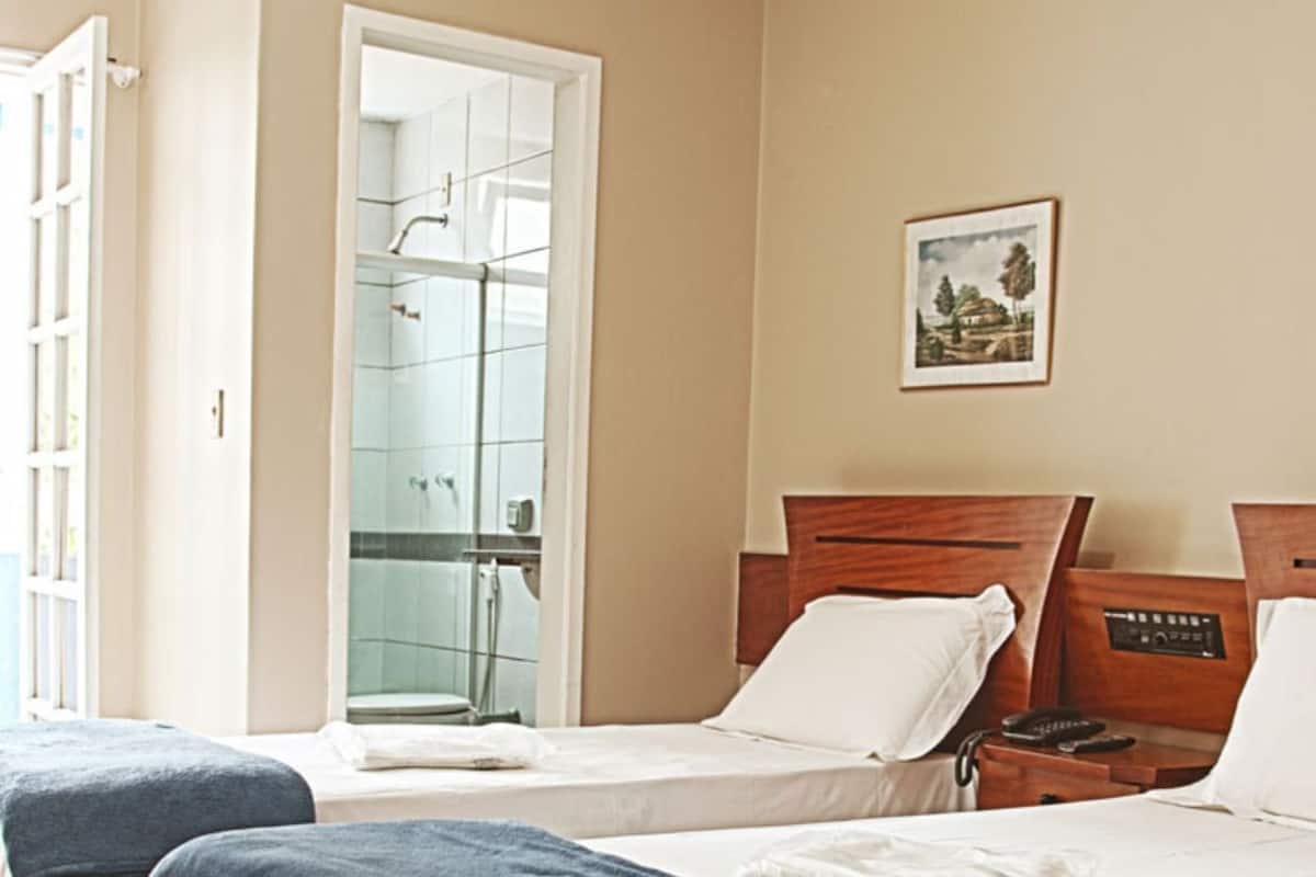 A hotel room with two beds, a shower, and a view of the outdoors.