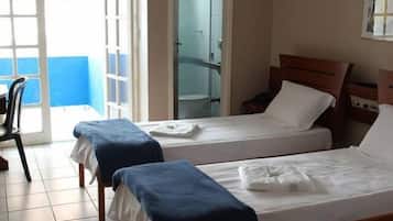 Habitación de hotel con dos camas, una silla y un ventanal que da a un balcón.