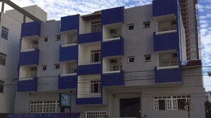 Un hotel de varios pisos con fachada azul y blanca, balcones y entrada porticada.
