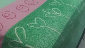 A bed with a green and pink bedspread, a red heart-shaped pillow, and a green and pink striped pillow. - Vila Mirante (Campina Grande)