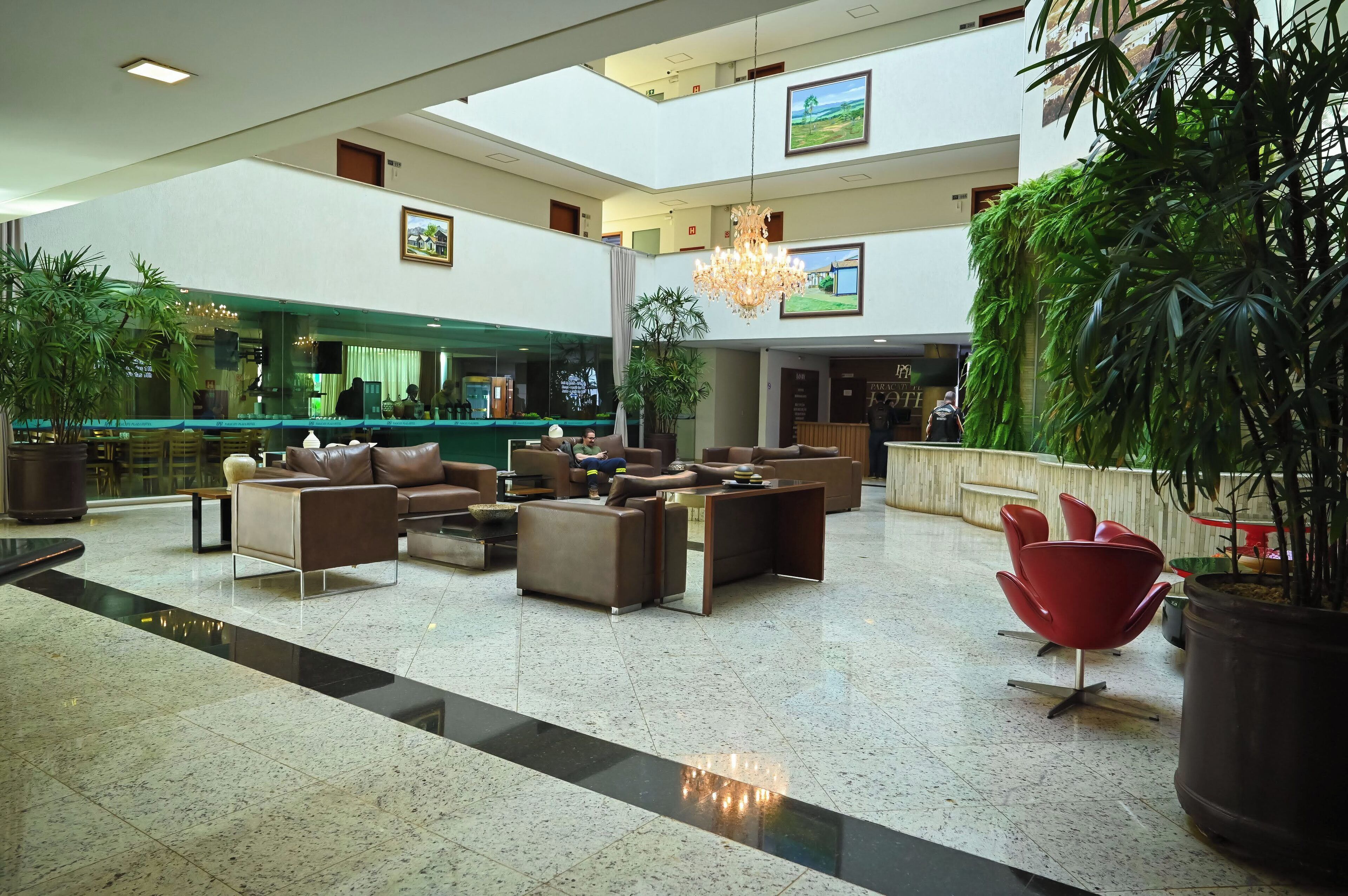 A spacious lobby with multiple seating areas, a reception desk, and large potted plants.
