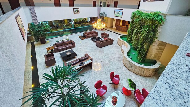 A spacious lobby with multiple seating areas, a reception desk, and a pool area. - Paracatu Plaza Hotel (Paracatu)