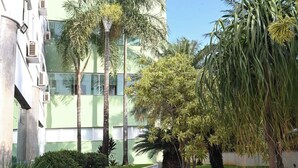 A modern building with multiple floors, a paved pathway, and several potted plants. - Paracatu Plaza Hotel (Paracatu)