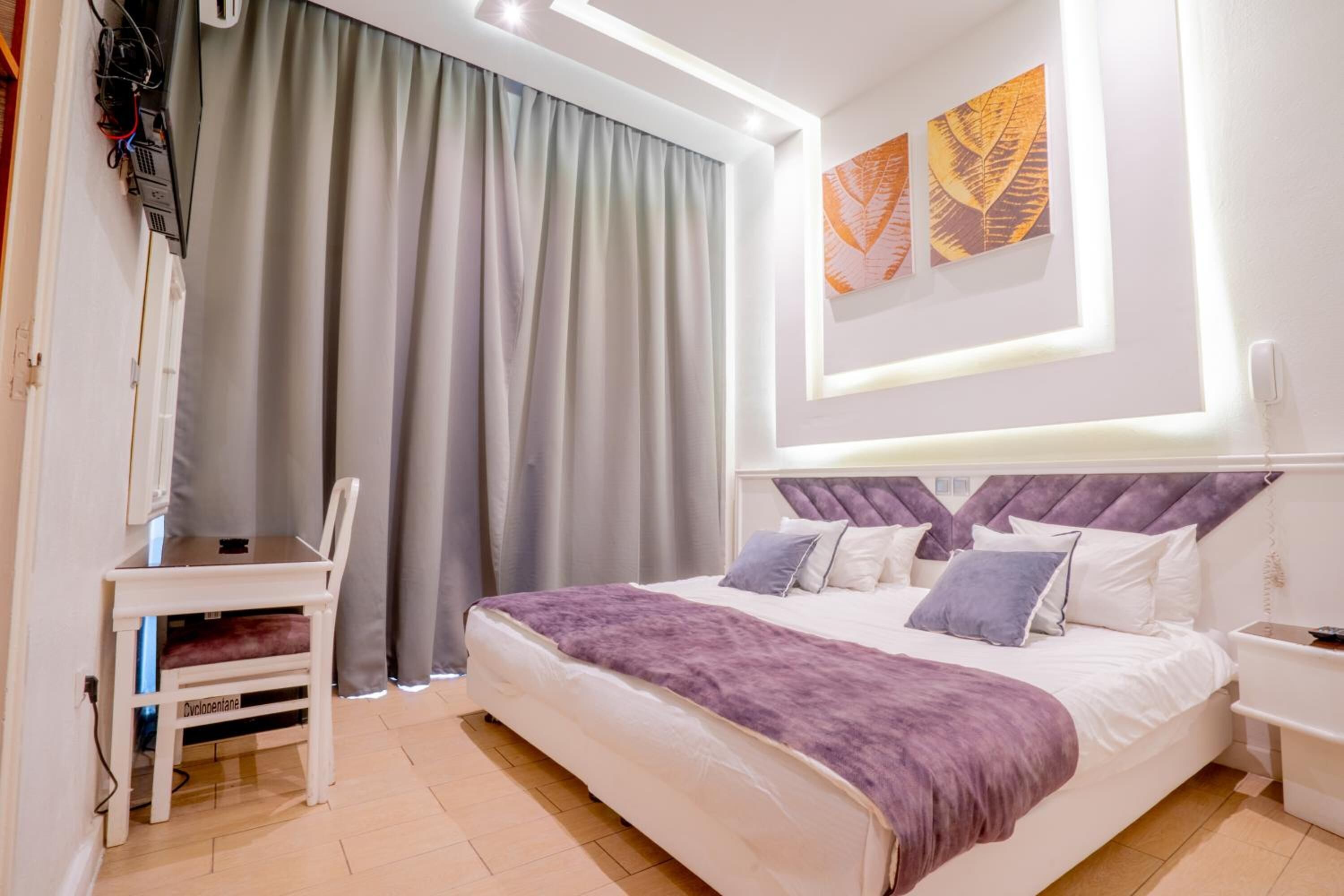 A modern bedroom with a large bed, a desk, and a chair.