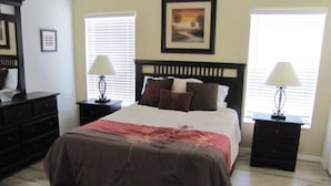 A bedroom with a bed, two nightstands with lamps, a dresser, and a painting on the wall. - 5 Br Pool Home with Spa in Aviana (Davenport)