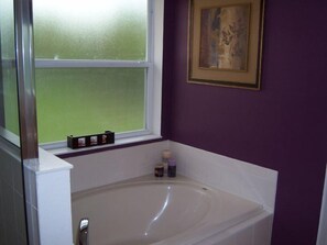 Une salle de bain avec une baignoire, une fenêtre et une œuvre d’art encadrée au mur.