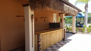 A thatched-roof outdoor bar area with a TV, bamboo decor, and a checkered floor. - 5 Br Pool Home with Spa in Aviana (Davenport)