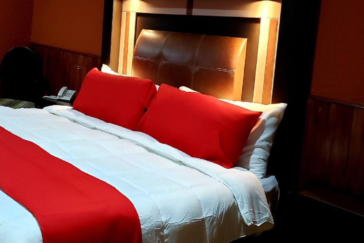 Een hotelkamer met een bed, nachtkastje en telefoon.